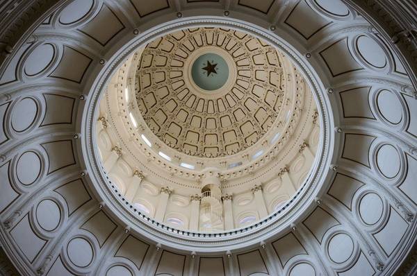 Interior shot looking up at the ceiling of the Texas State Capitol Building, which features the iconic lone star at the top of the dome.
