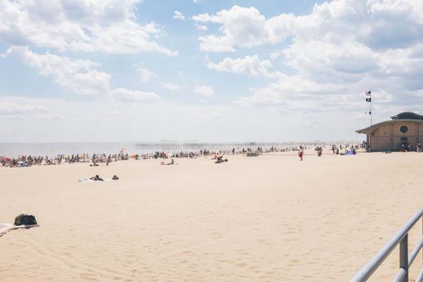 Bright sand and fluffy white clouds on a busy sunny day at Coney Island Beach in NYC