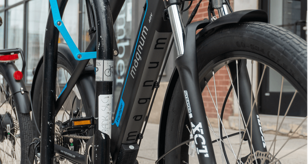 Black and blue Magnum Voyager e-bike locked to a bike rack using a Foldylock