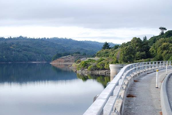 A bridge with guardrails overlooks serene still water at the Crystal Springs Dam along the Crystal Springs Regional Trail for e-bike rides in San Mateo County
