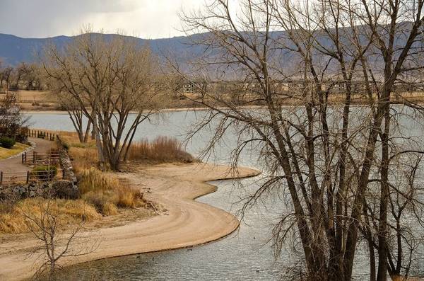 A photo of the High Line Canal Trail at McLellan Reservoir in Littleton with a paved e-bike path winding through a grassy area and trees on either side