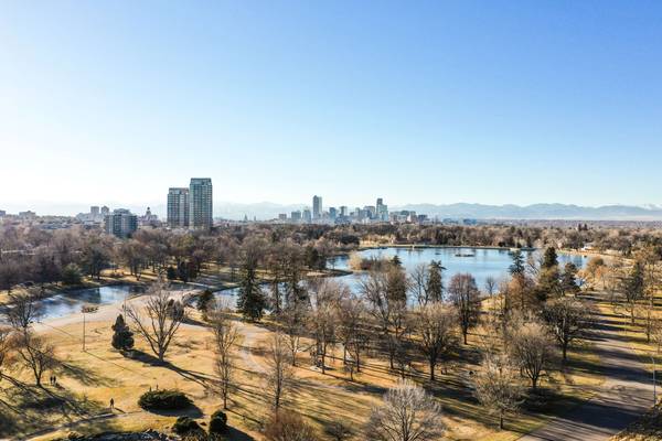 Aerial view of City Park in Denver, Colorado in winter, showing a lake beyond dry grass and barren trees on a clear sunny day
