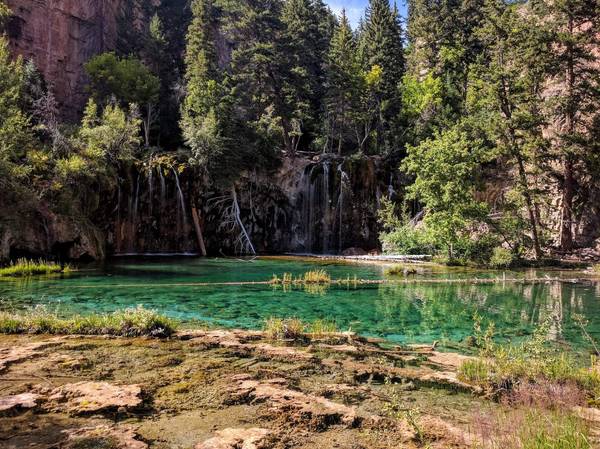 Clear turquoise water surrounded by steep tree-lined cliffs in Glenwood Springs, Colorado