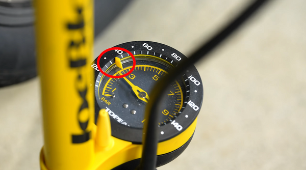 Upclose gauge on a tire pump, with a superimposed red circle highlighting a marker that can be used to set your preferred tire pressure