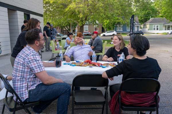 A group of people sitting around a table are all laughing, while other attendees eat and converse in the background