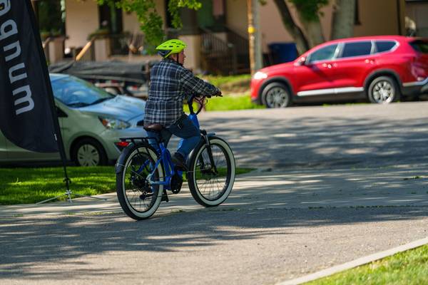 A man in black and white flannel and neon yellow helmet test drives a blue Magnum Pilot e-bike