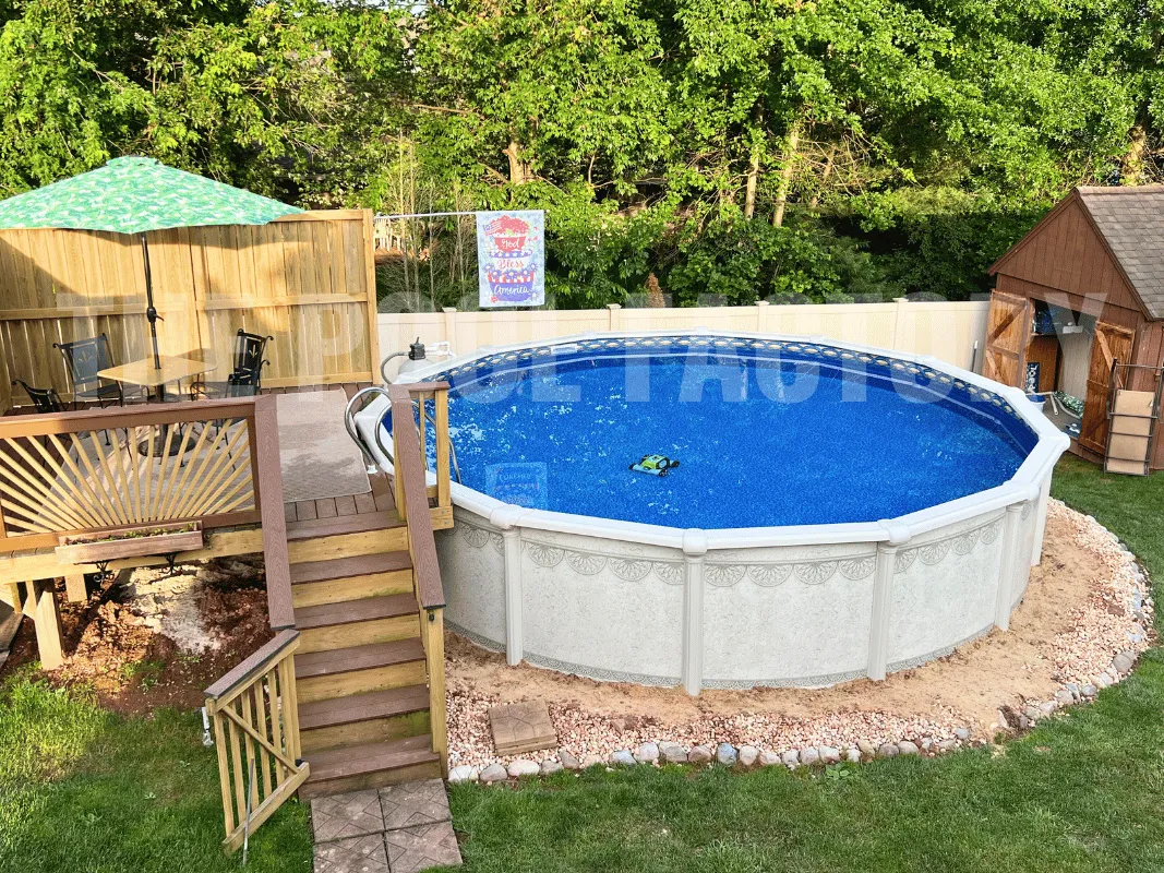 Round above ground pool with partial deck, backyard loungers, and manicured green lawn