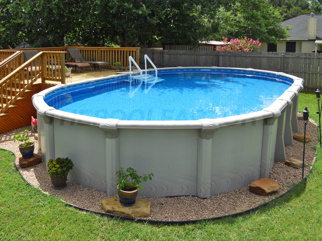 Oval above ground swimming pool with a partial deck and flower pots surrounding pool