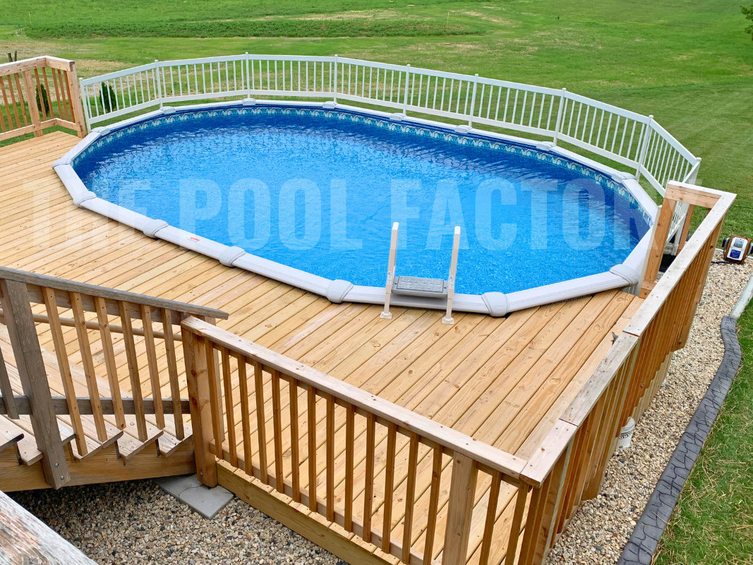 Oval swimming pool with full deck, safety fence, and landscaping