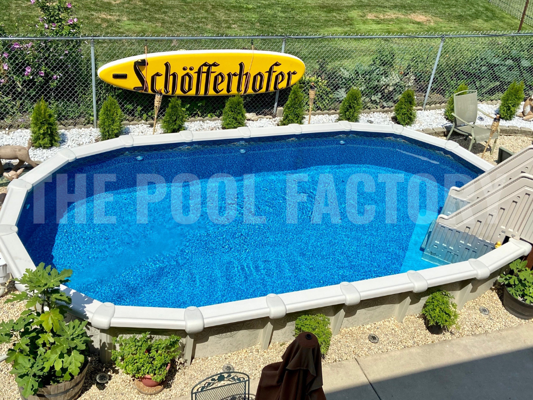 Oval semi-inground pool with lush green shrubs surrounding pool, on a sunny day