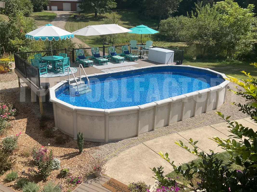 Oval above ground pool with deck, grass, and patio furniture on a sunny day