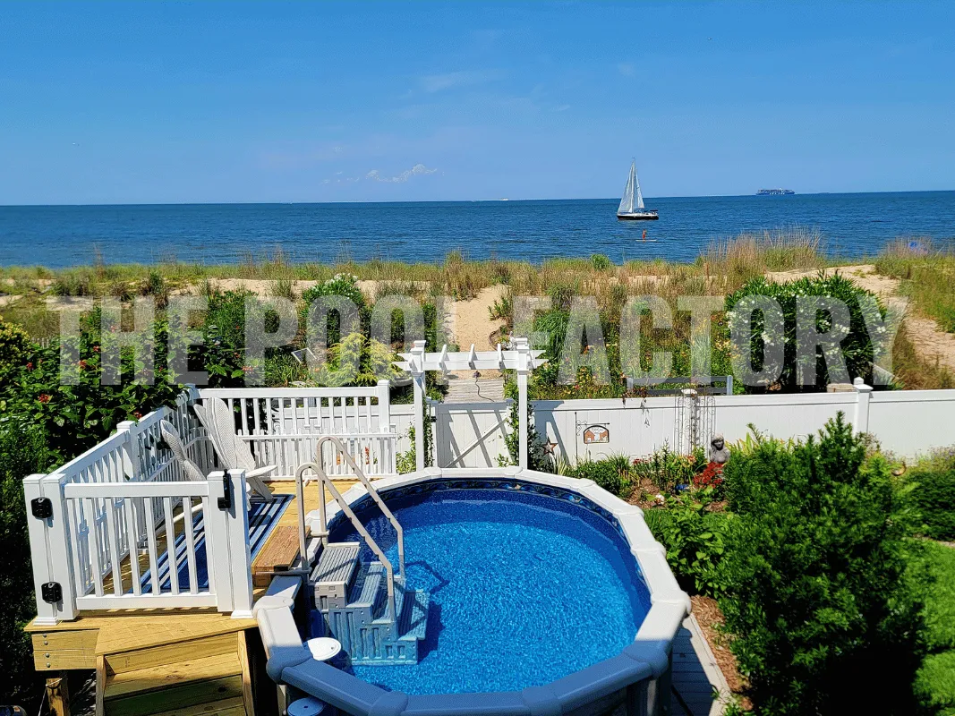 Oval semi-inground pool with scenic backdrop of the bay and sailboat and partial deck