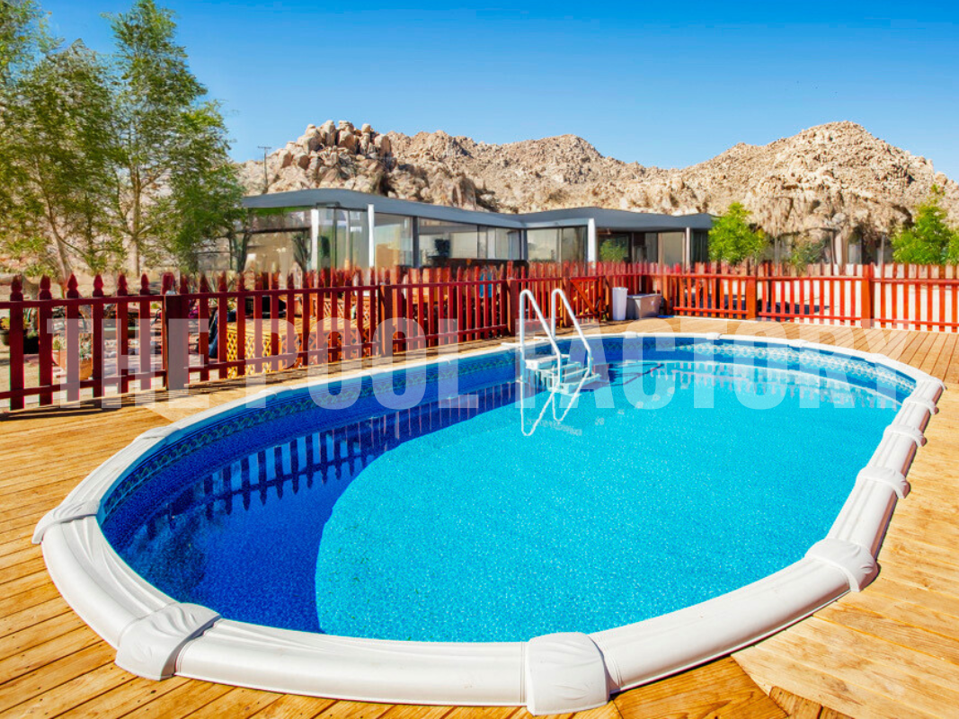 Oval semi-inground swimming pool with wrap around wooden deck and decorative rock landscaping