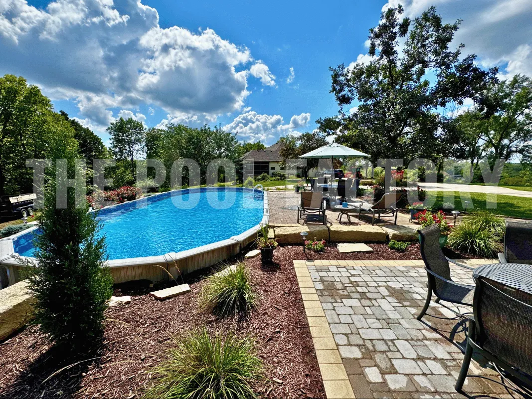 Oval semi-inground pool with landscaped surroundings and stone paver patio