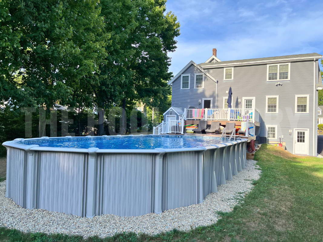 Above ground oval swimming pool with partial deck, surrounded by decorative rocks
