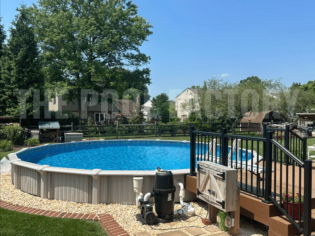 Round semi-inground pool with manicured pebble border, partial wooden deck, and landscaped yard