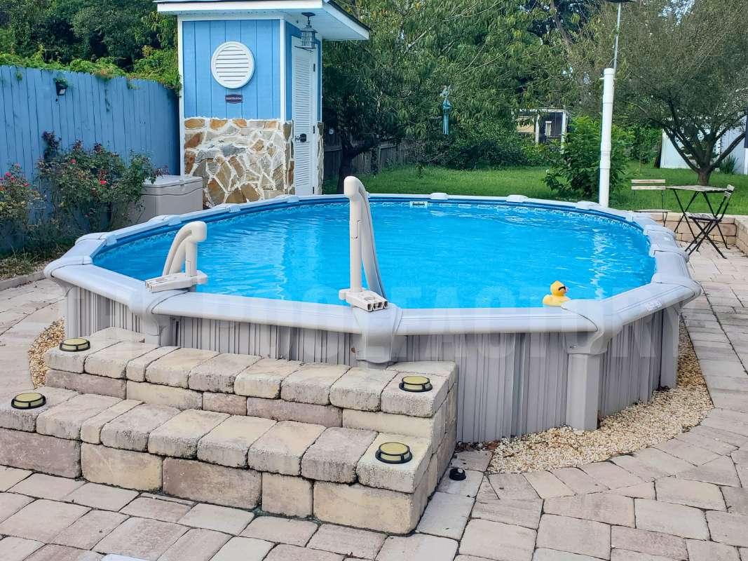 Semi-inground oval swimming pool with stone patio and steps