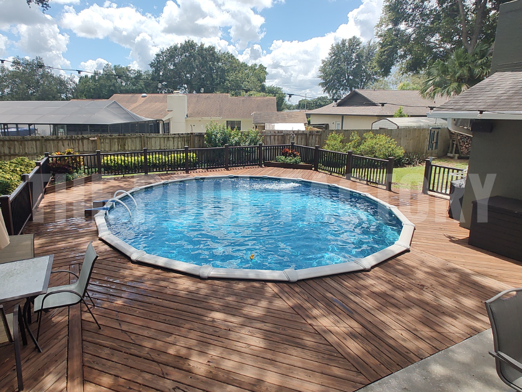 Round swimming pool with full deck, surrounded by lush greenery
