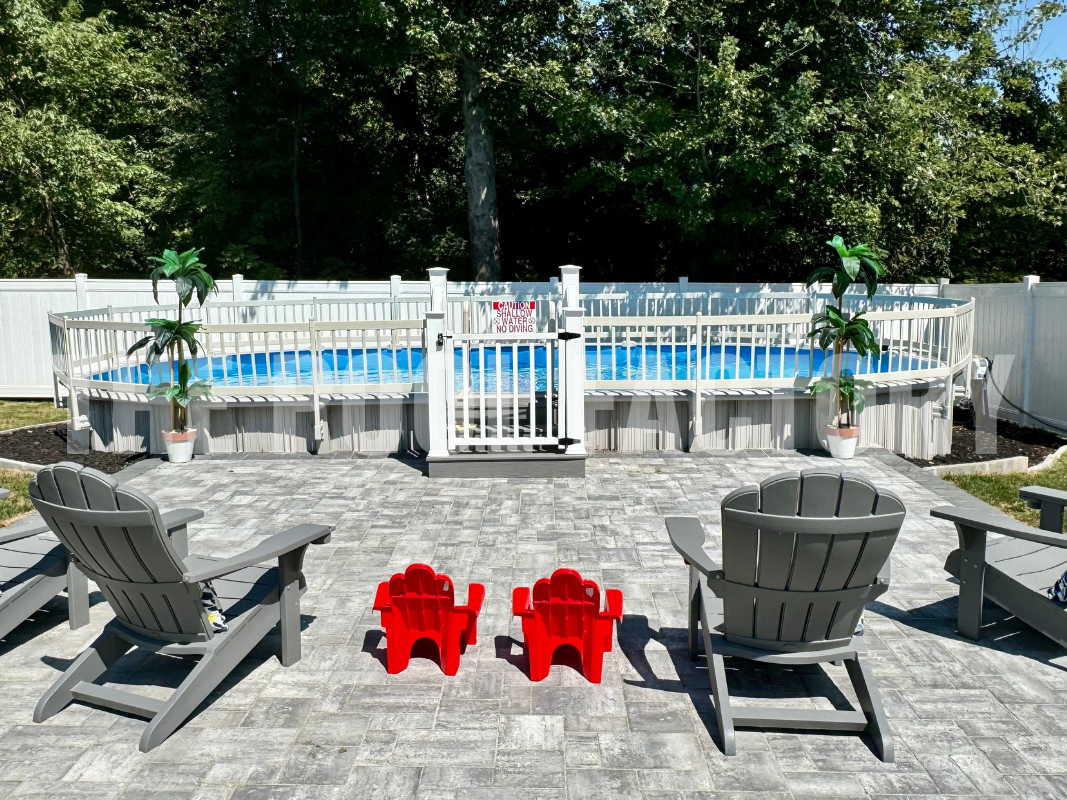 Oval semi-inground swimming pool with safety fence and patio chairs