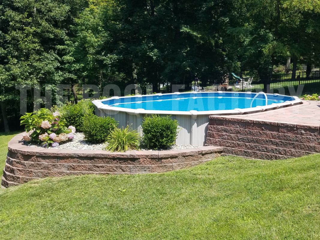 Semi-inground oval pool surrounded by trees and stonework