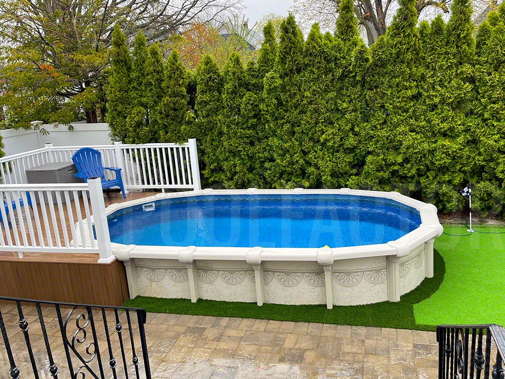 Oval semi-inground swimming pool with privacy hedges and a small deck for easy access