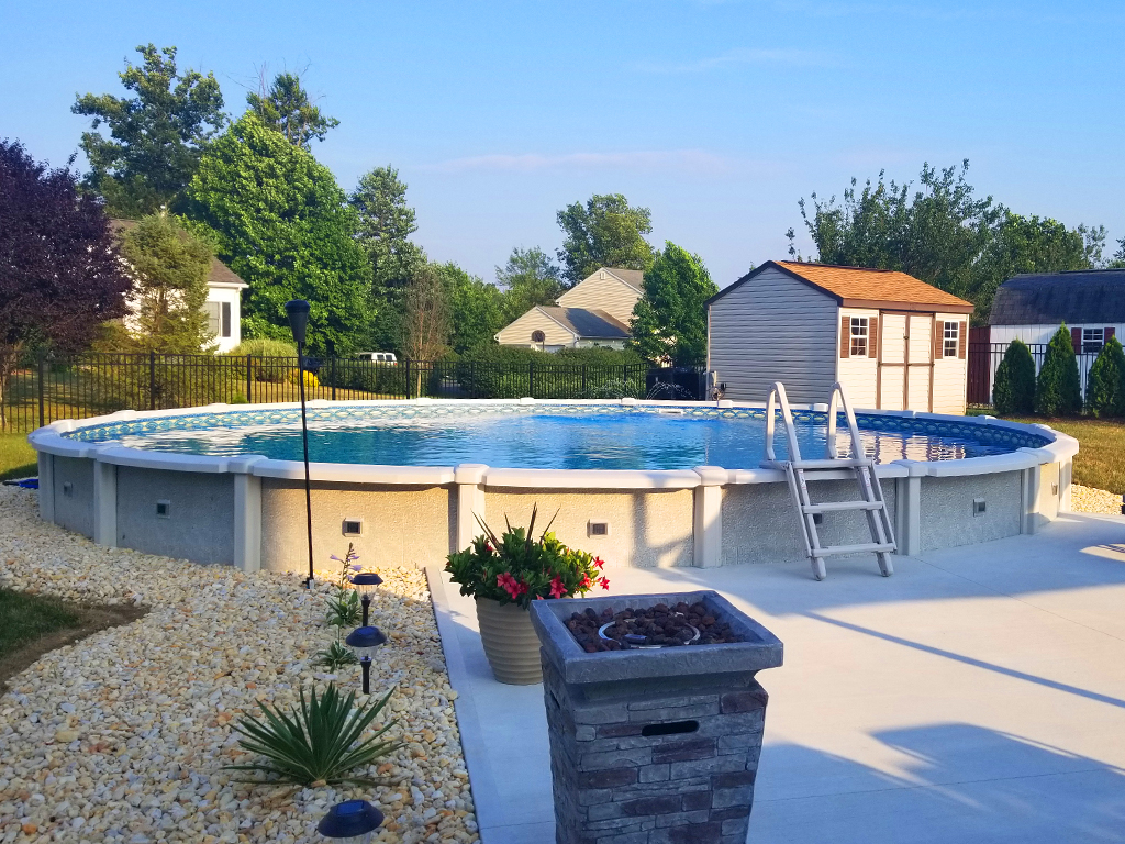 Semi inground saltwater swimming pool with concrete patio and decorative stone surrounding