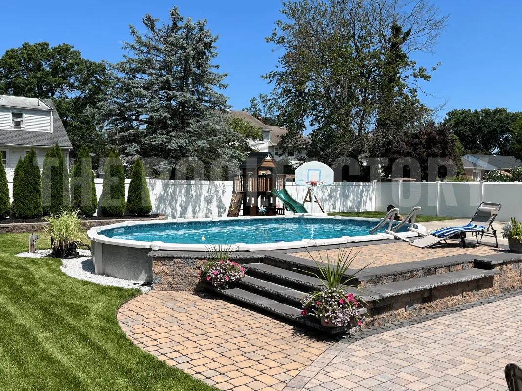 Backyard oval saltwater pool with paver patio & deck, lounge chairs, and green grass