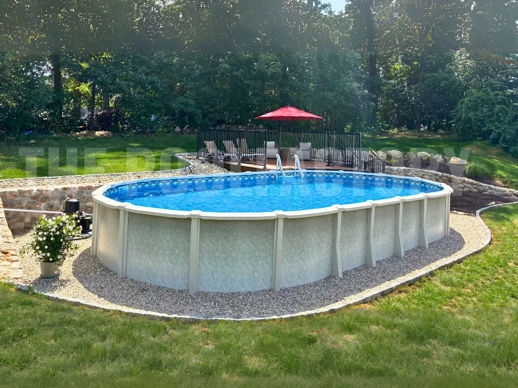 Above ground oval saltwater pool surrounded by tall trees and stone retaining wall