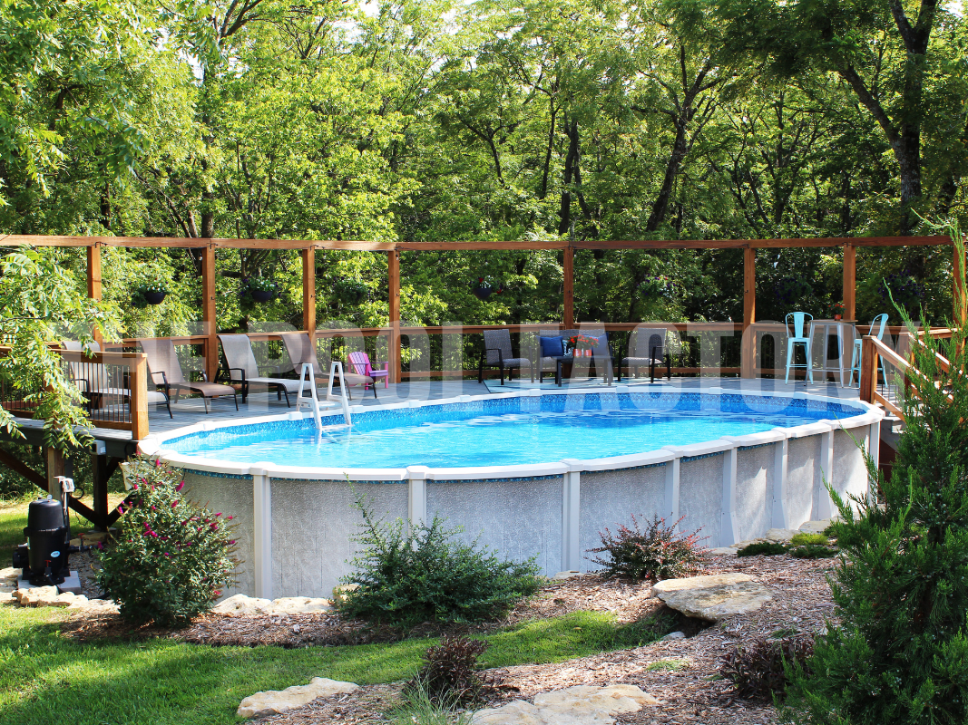 Above ground saltwater swimming pool with partial deck, lounge chairs, shrubs and greenery on a sunny day