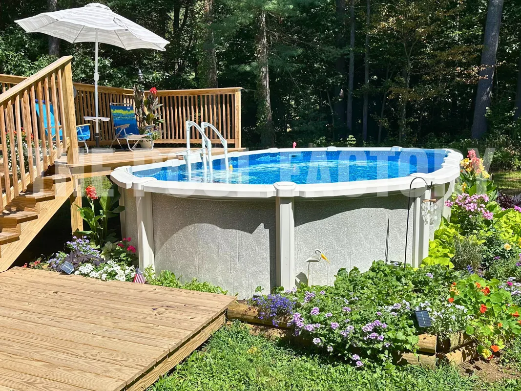 Oval above ground saltwater pool with garden flowers, grass, and wood deck