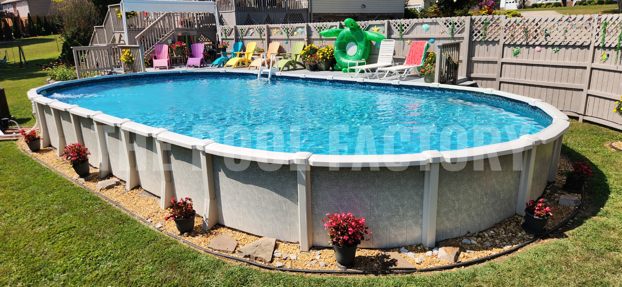 Above ground saltwater oval pool with flowering plants and colorful lounge chairs on deck