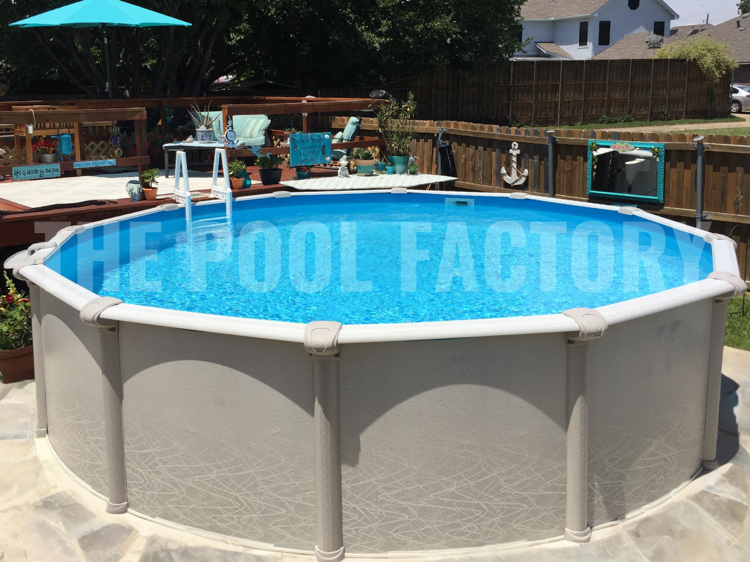 Round saltwater above ground swimming pool with stone patio, trees, and partial deck