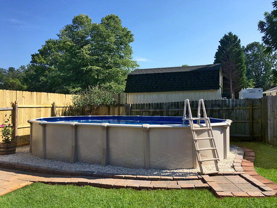 Oval above-ground saltwater swimming pool with a stone-paved walkway