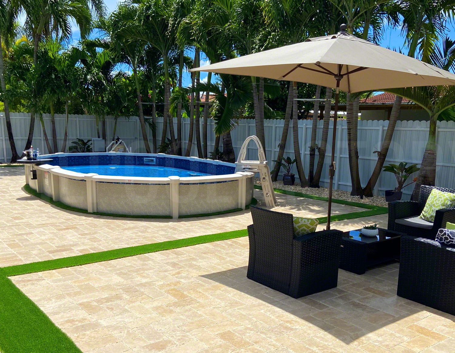 Semi inground saltwater pool with paver patio and tall palm trees surrounding