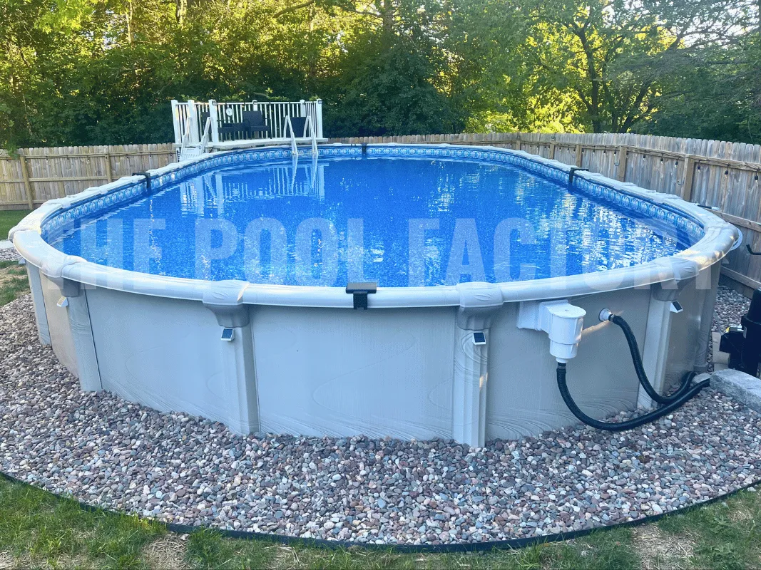 Oval saltwater semi-inground pool surrounded by manicured lawn and pebble edging