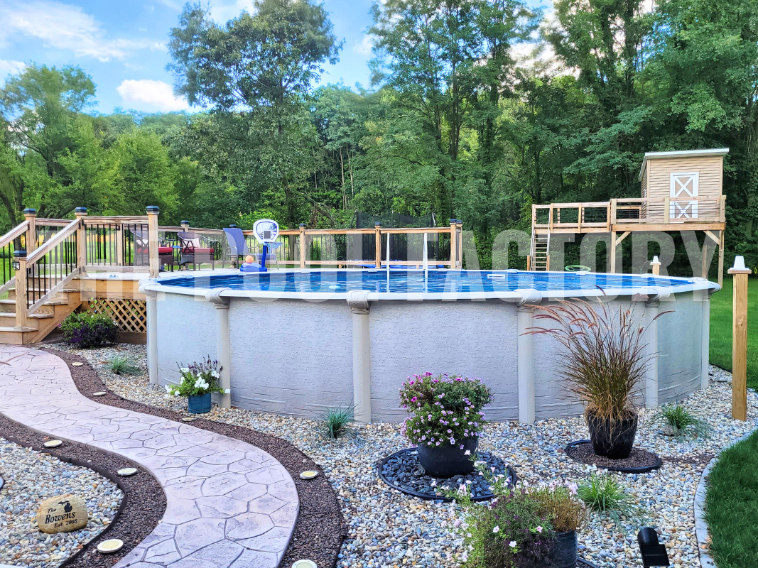Round above ground swimming pool with decorative stone pathway and partial deck with lounge chairs