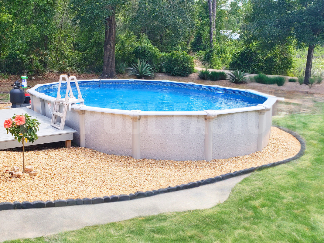 Semi-inground oval swimming pool with decorative stone and lush landscaping