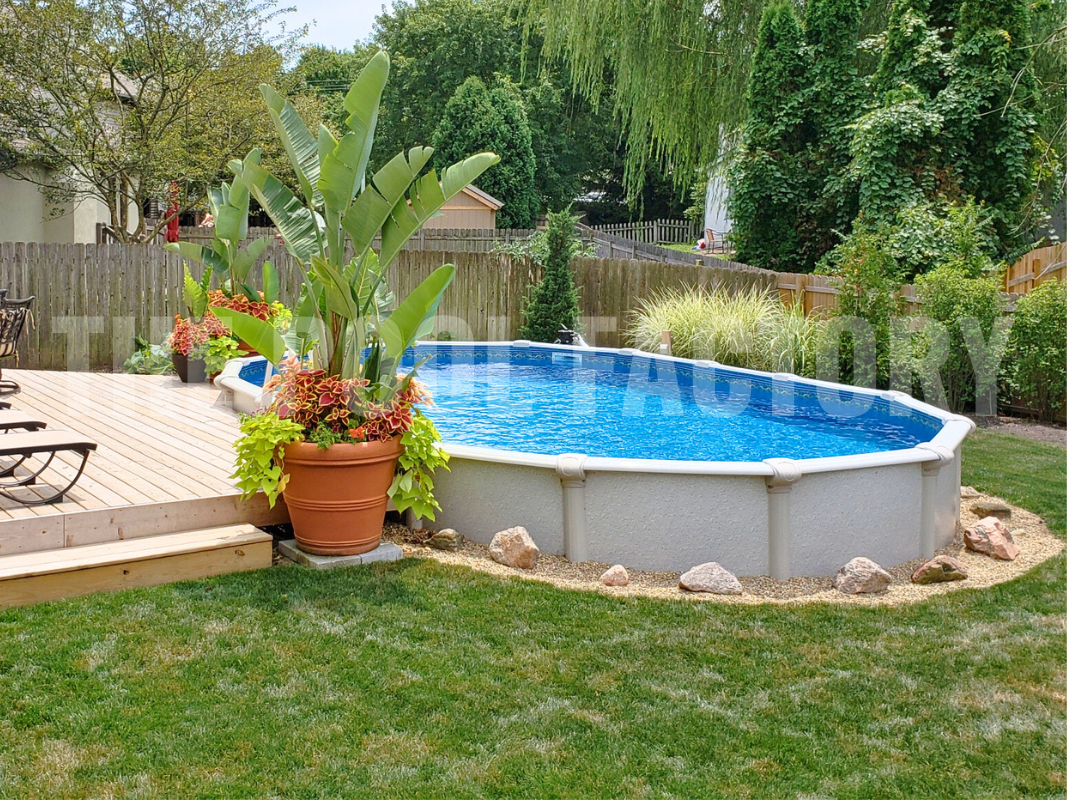 Oval semi-inground pool with decorative rocks surrounding and lush greenery