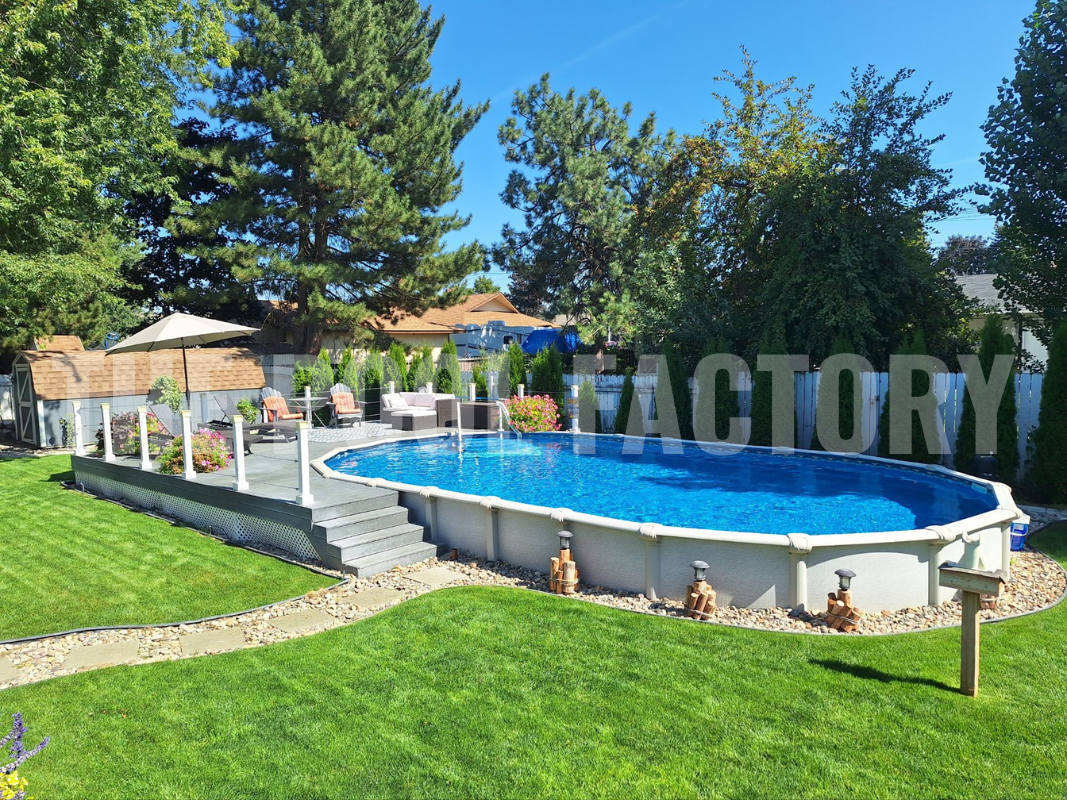 Oval semi inground swimming pool with decorative stone pathway, partial deck with lounge chairs and lush greenery