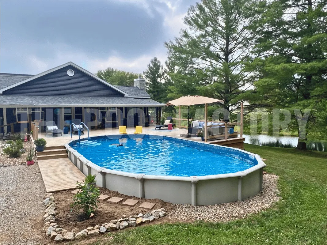 Oval above ground pool with partial deck, umbrella shade, and beautifully landscaped yard