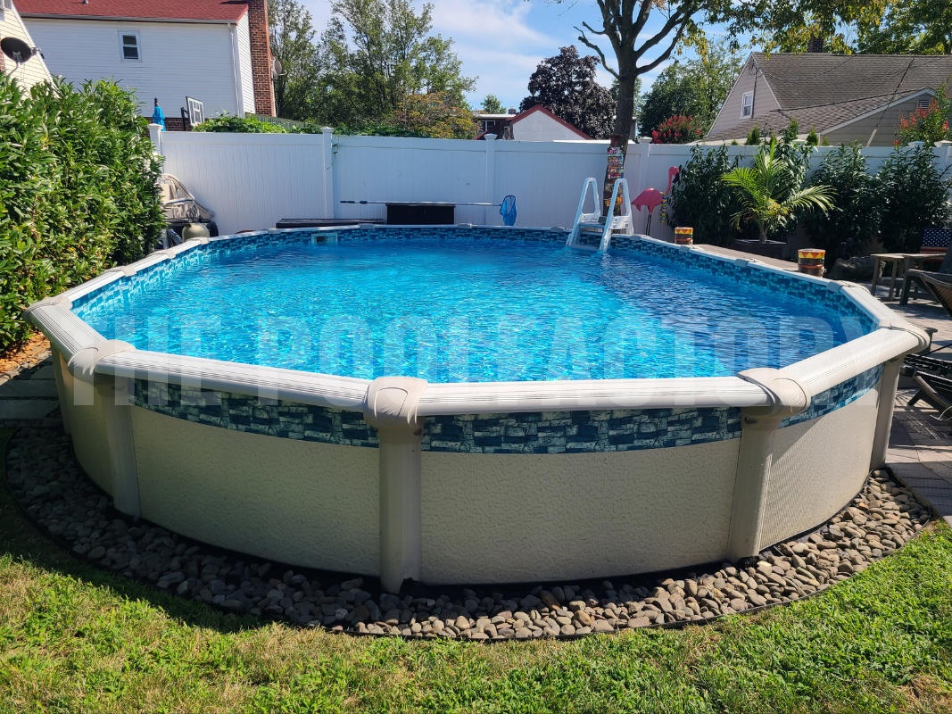 Oval semi inground pool with stone patio and decorative rock border surrounding