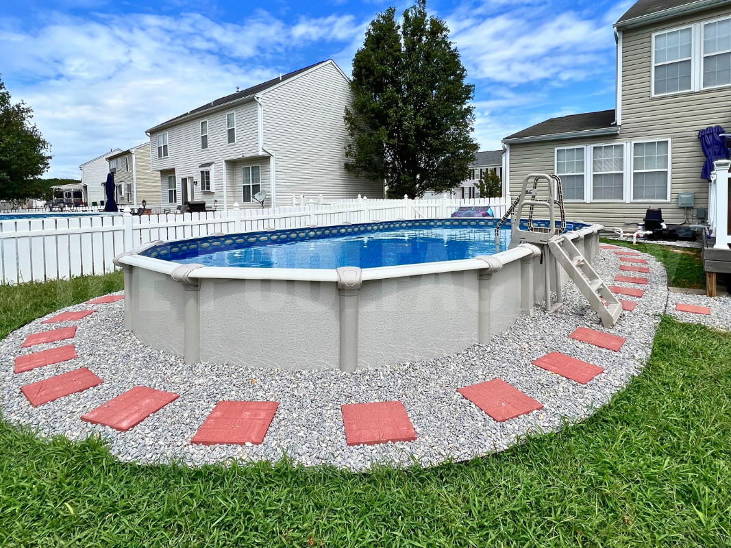 Oval semi inground saltwater swimming pool with decorative rocks and stone pathway surrounding