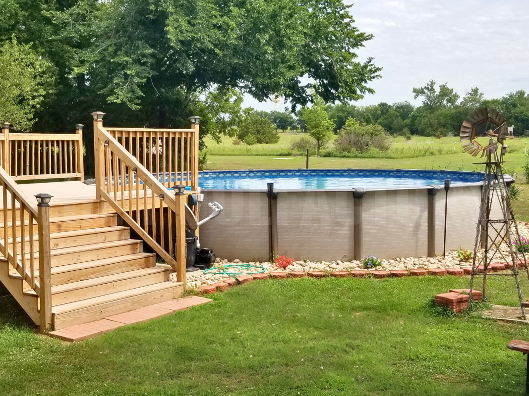 Above ground swimming pool with decorative rocks and partial deck access