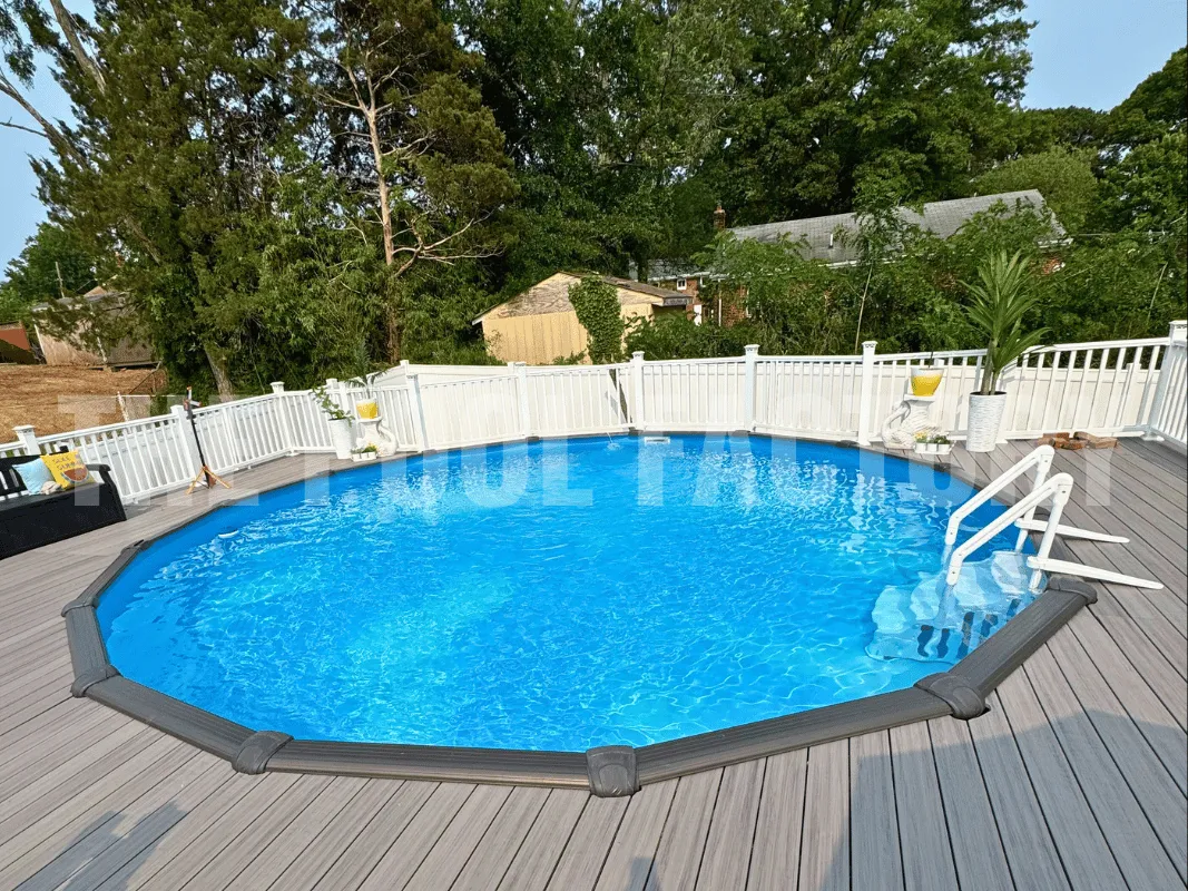Above ground swimming pool with gray composite decking and privacy fence