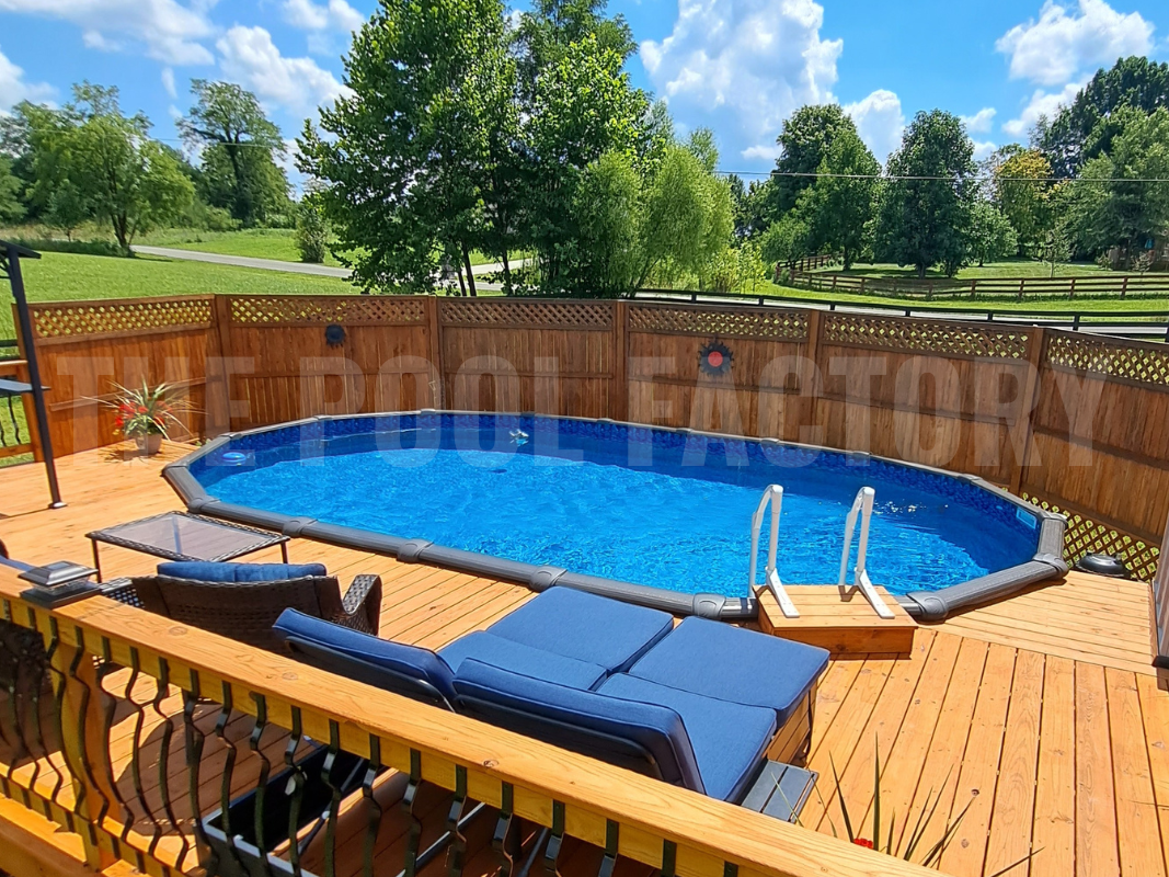 Oval swimming pool surrounded by a deck, and tall trees