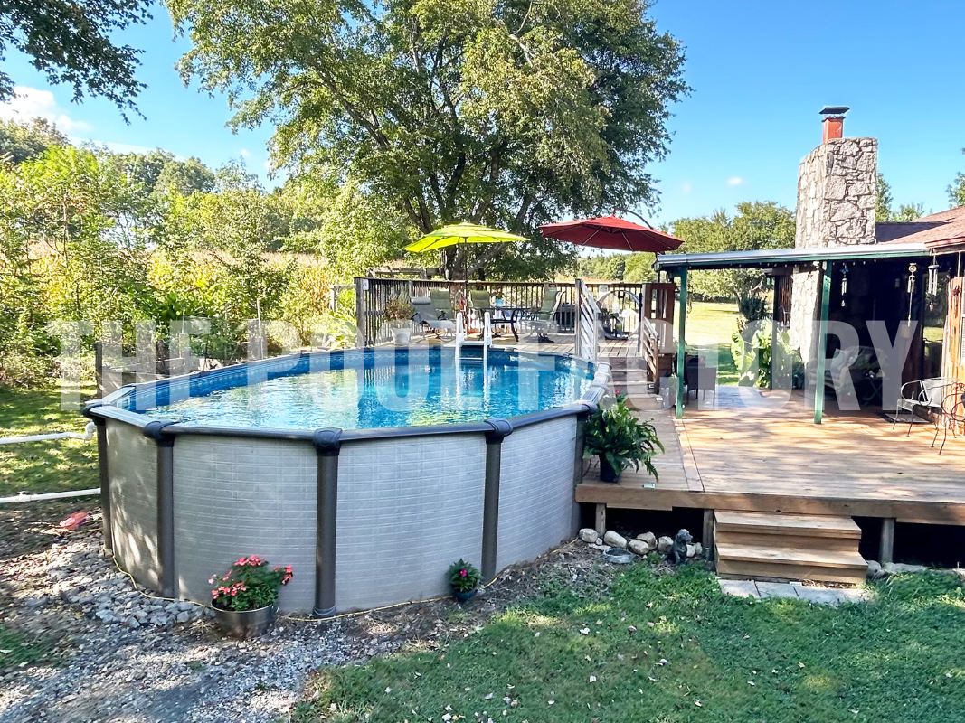 Backyard with an oval above ground swimming pool, decorative rocks, and plants