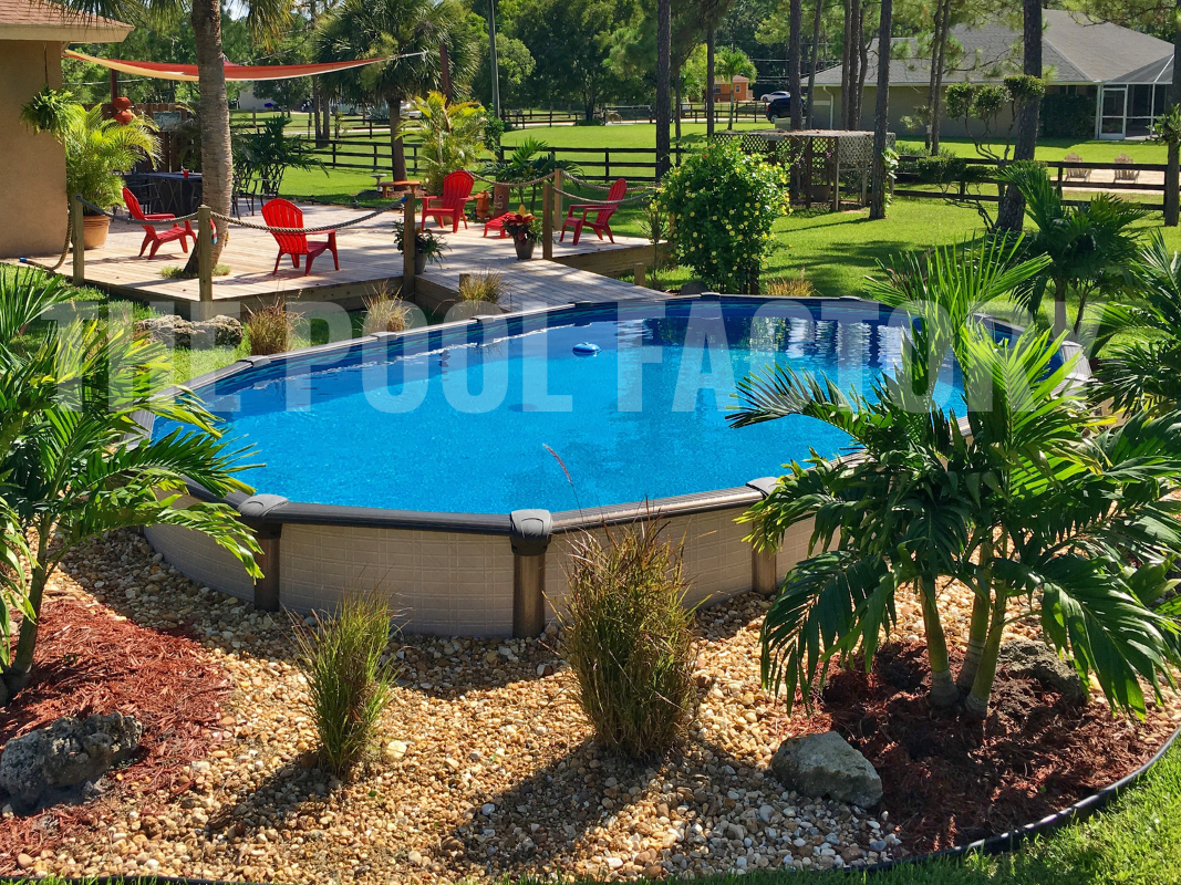 Semi-inground oval swimming pool with tall palm trees and a garden backdrop