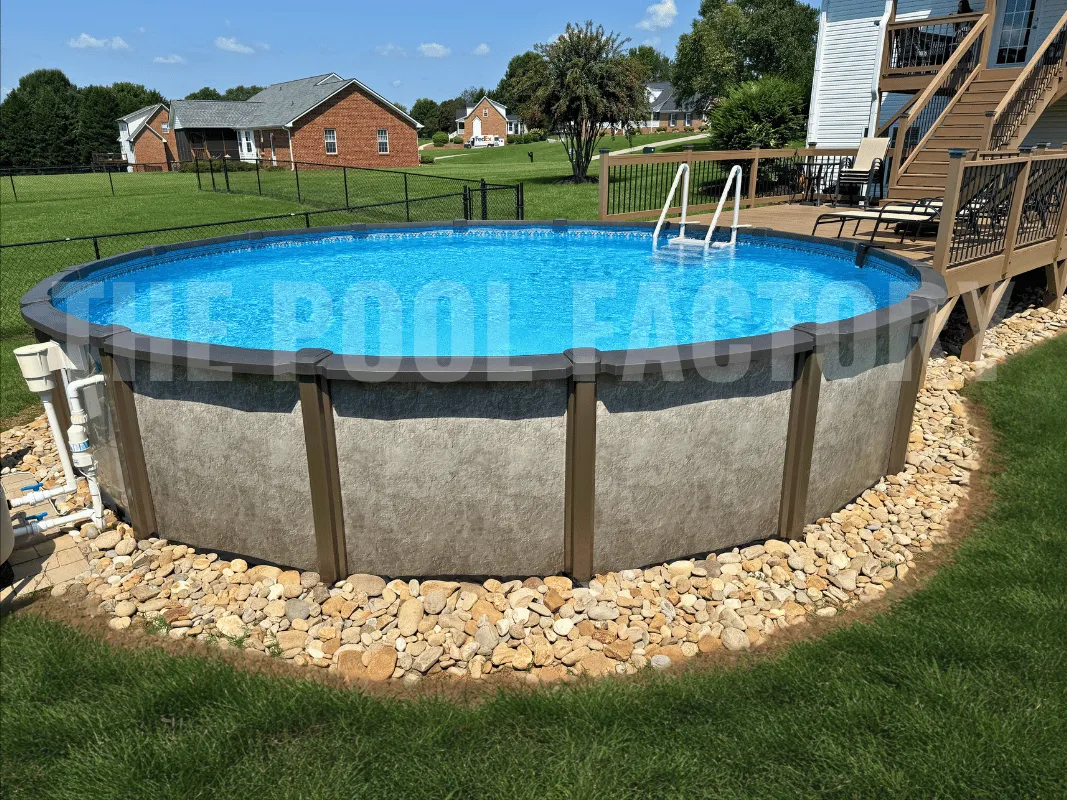 Round above ground pool with grass & stone border, partial deck, and bright sunlight