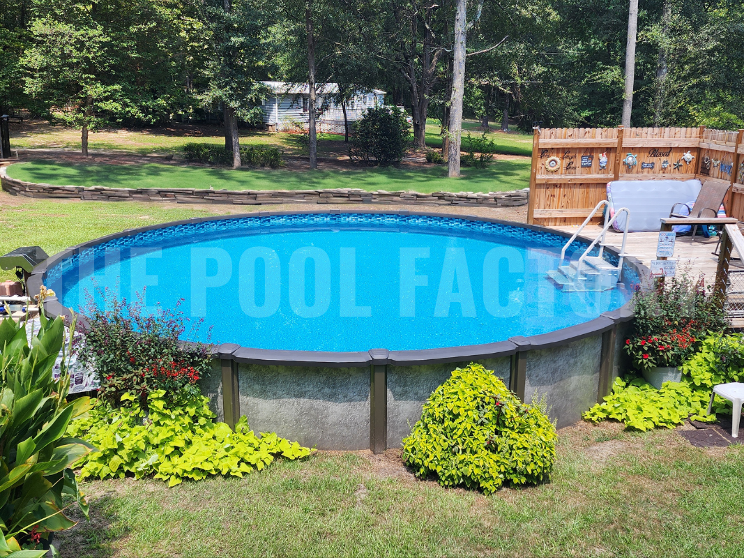 Round above ground swimming pool with large shrubs and partial deck