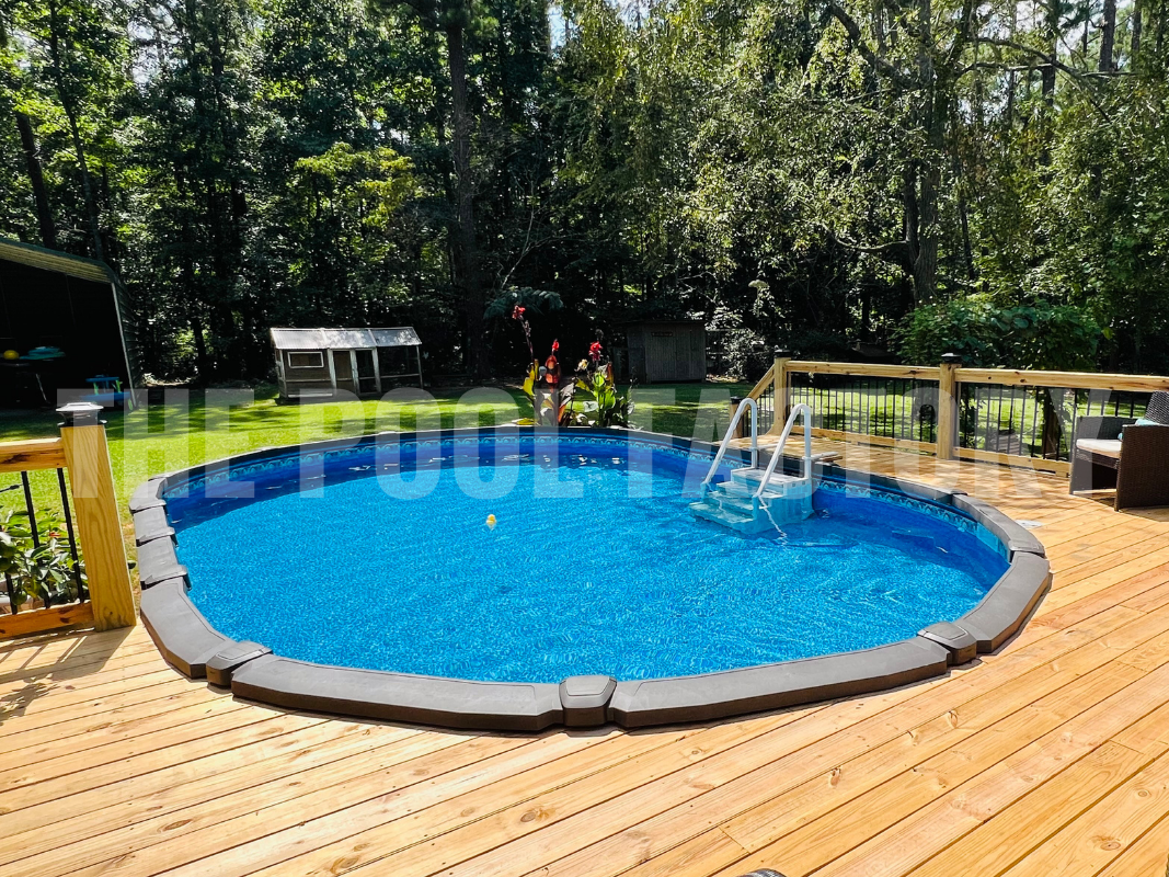 Above ground oval pool with partial deck and greenery on a sunny day